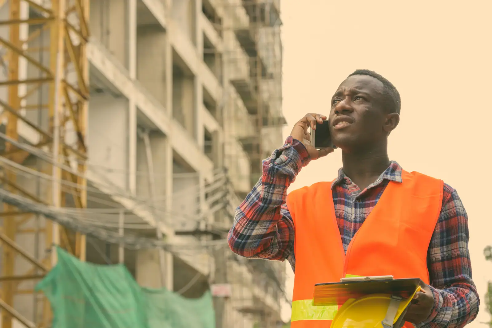 Construction supervisor taking a call on site with clipboard in hand