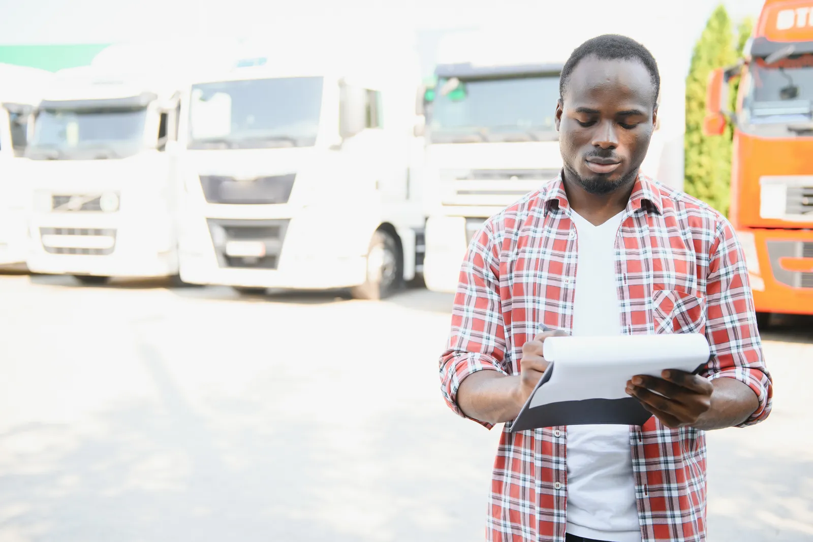Site controller checking a materials delivery against a clipboard at a Ghana site gate