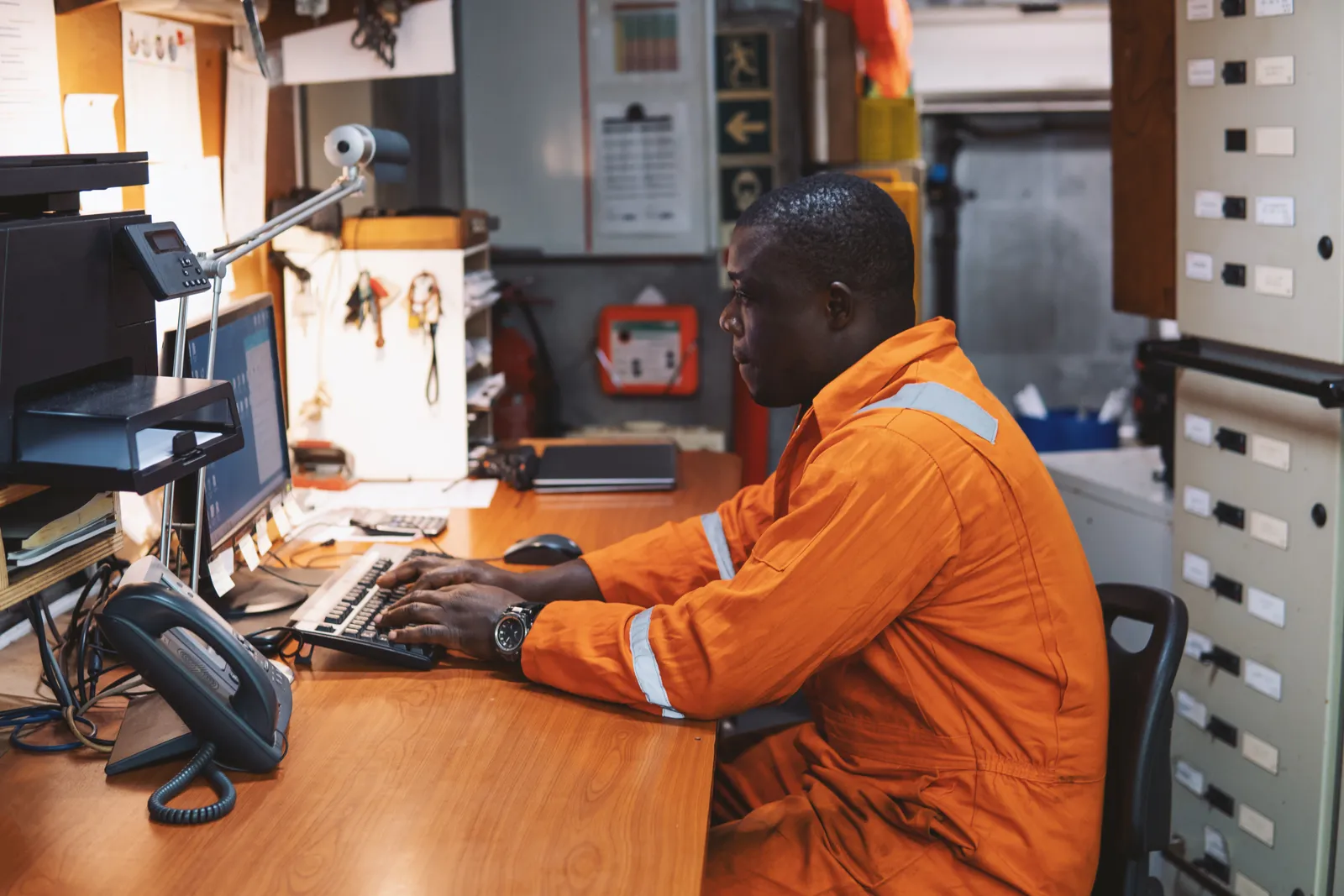 A site foreman working the operating record at a Ghana back-office desk