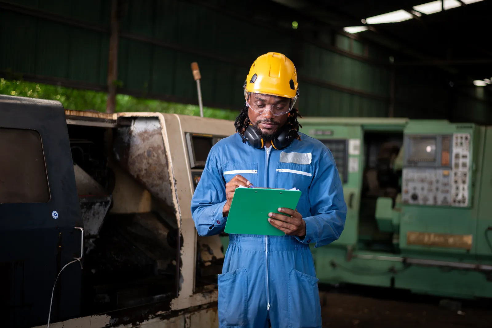 Technician logging a machine inspection on a clipboard in a Ghana workshop