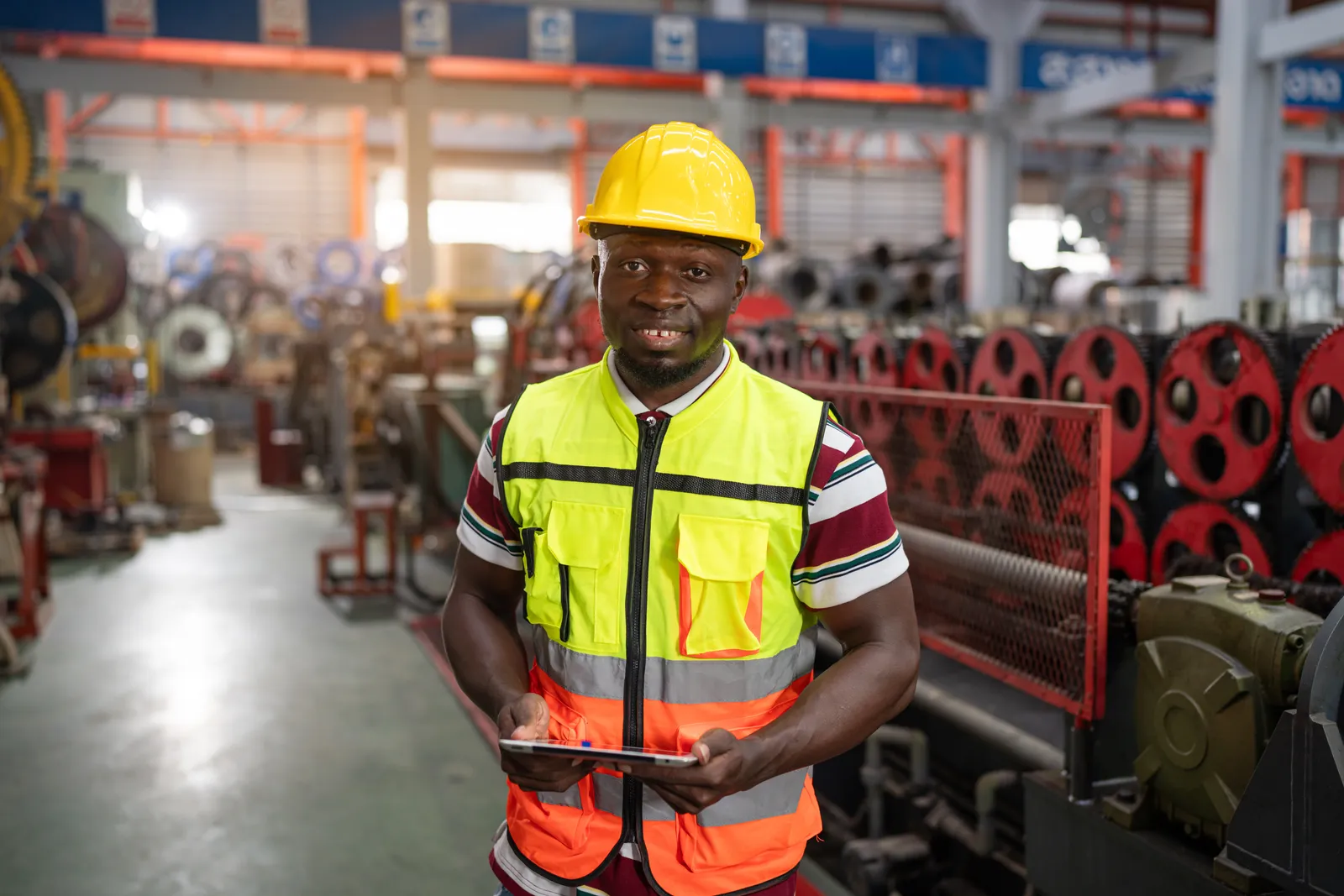 Site engineer checking machine status on a tablet in a Ghana workshop
