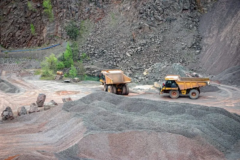 Yellow dump trucks lined up at a gravel quarry